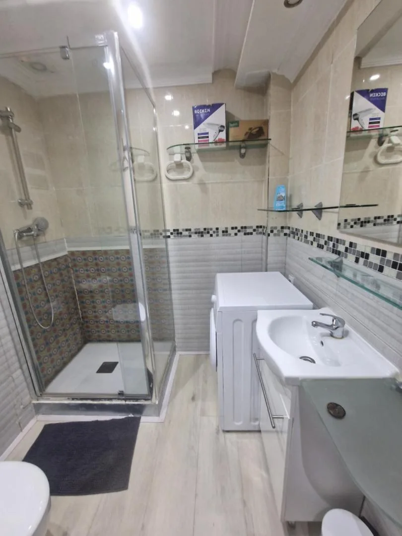 Baño con ducha de cristal y lavabo blanco