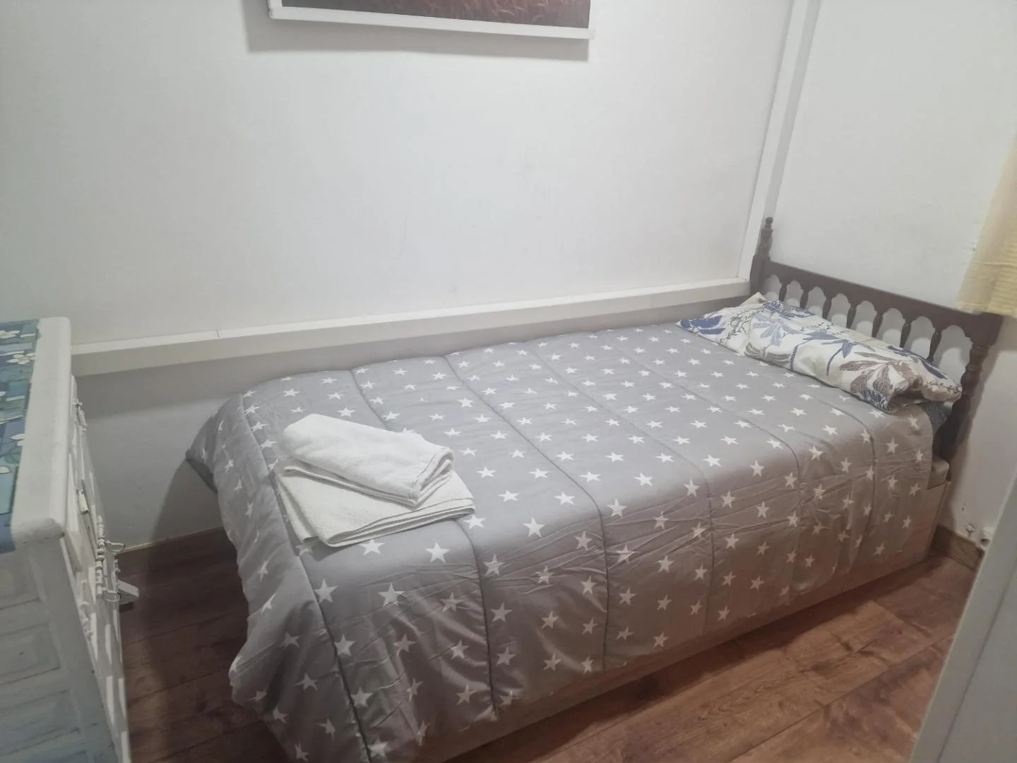 Dormitorio con cama de madera y colcha gris